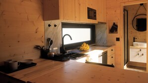 A compact kitchen with wooden walls, a built-in microwave, and a small sink. - Quinta da Quinhas (Caminha)
