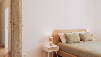 A bedroom with a wooden bed, white nightstand, and a small white table.