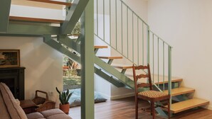 A staircase with a green railing leading to a landing. There is a wooden chair with a patterned cushion on the landing. - Quinta da Quinhas (Caminha)