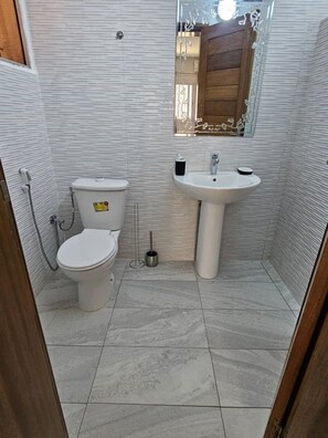 Un baño pequeño y funcional con inodoro, lavamanos y espejo.
