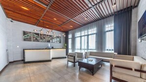 A spacious living area with a wooden ceiling, a sofa set, a coffee table, and a kitchen area with a white countertop and appliances. - Changshou Manhu Yashe Hotel (Chongqing)