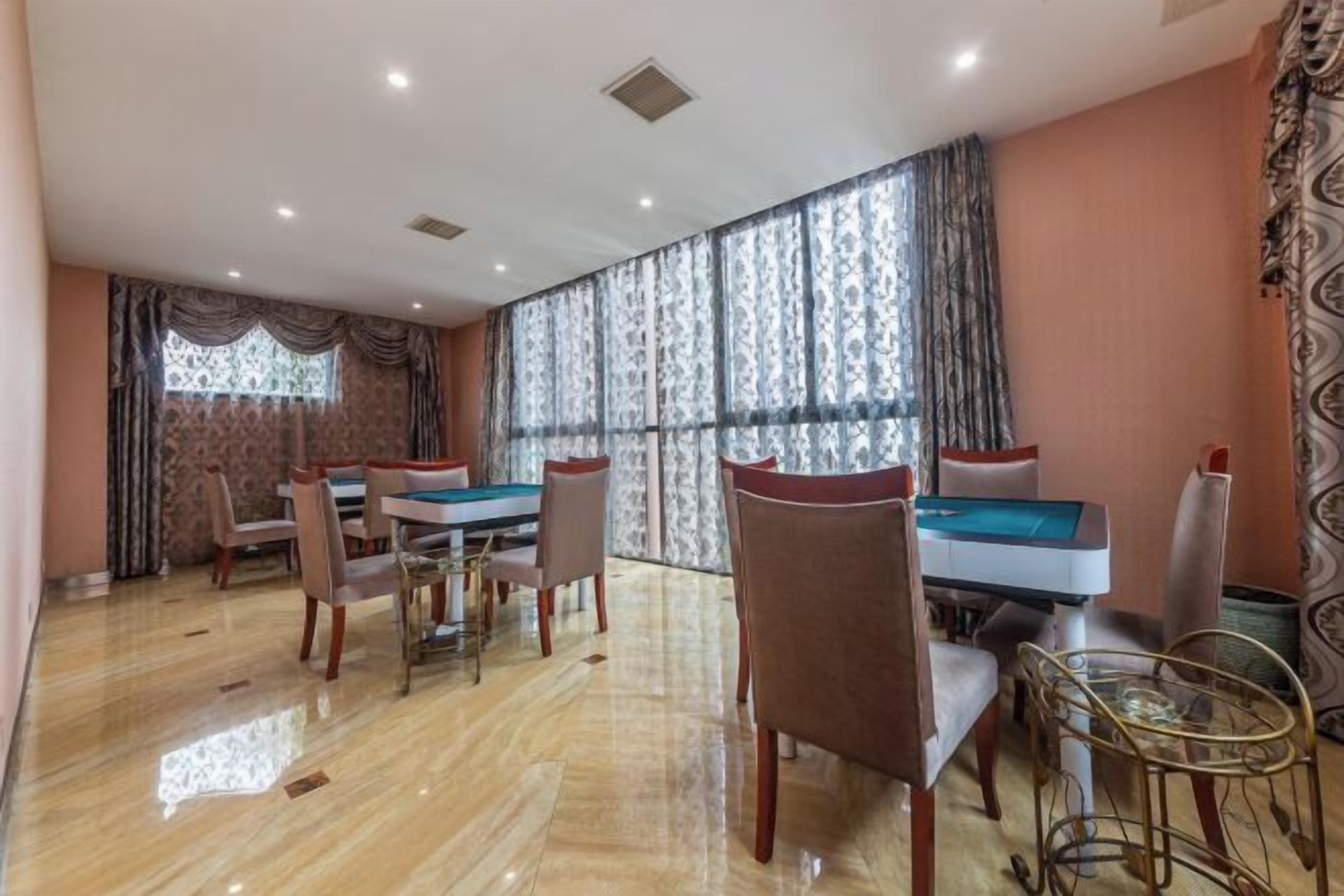 A dining area with a pool table, chairs, and a large window with patterned curtains.