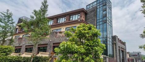 A multi-story building with a modern glass facade, surrounded by greenery and a well-maintained lawn.