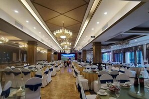 A banquet hall with rows of tables, chairs, and a central stage. - Changshou Manhu Yashe Hotel (Chongqing)