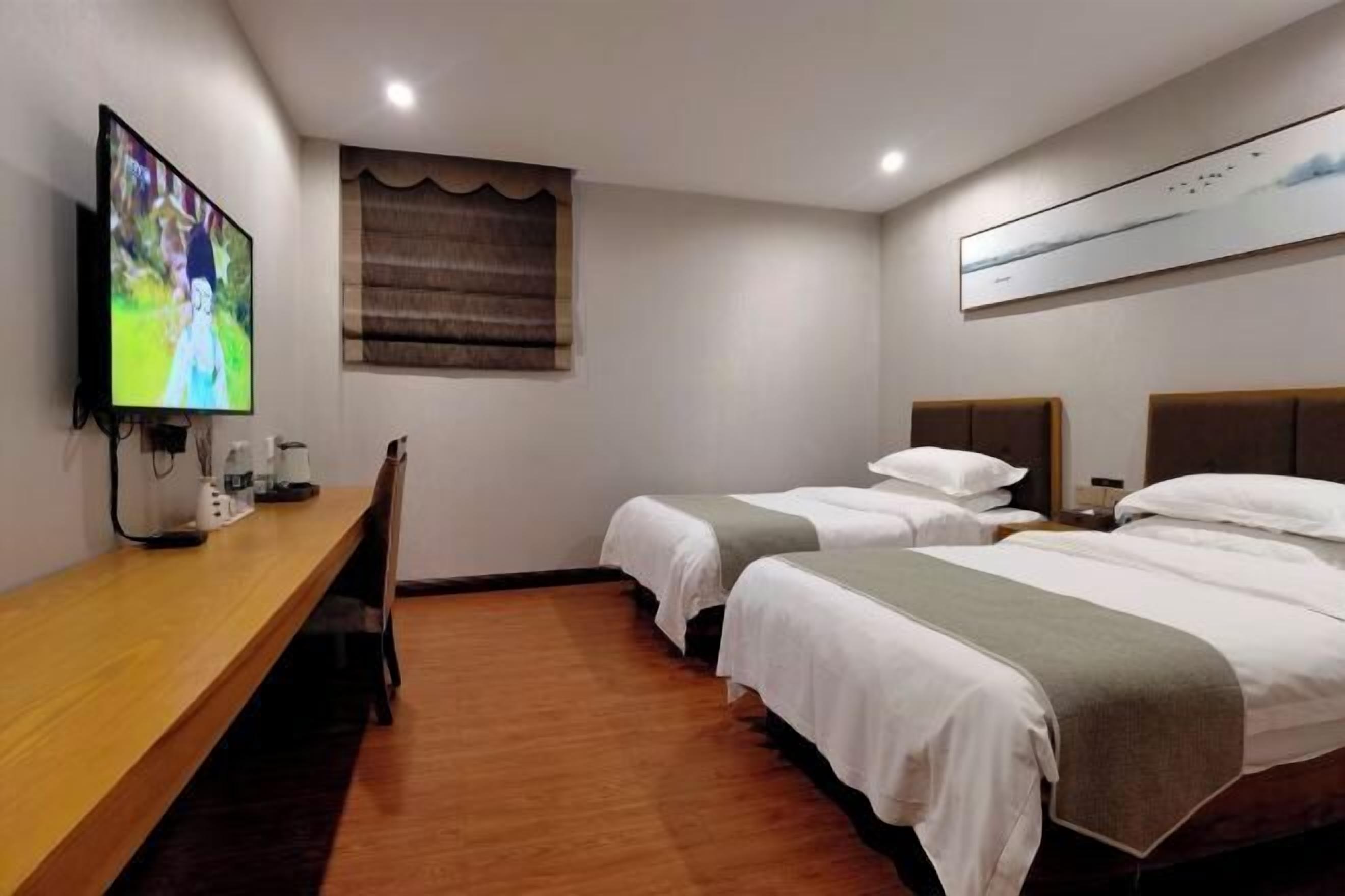 Une chambre d’hôtel avec deux lits, une télévision, un bureau en bois et une fenêtre avec des rideaux.