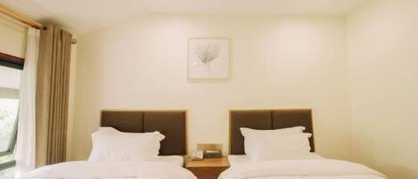 A hotel room with two beds, a nightstand, a framed picture on the wall, and a window with curtains.