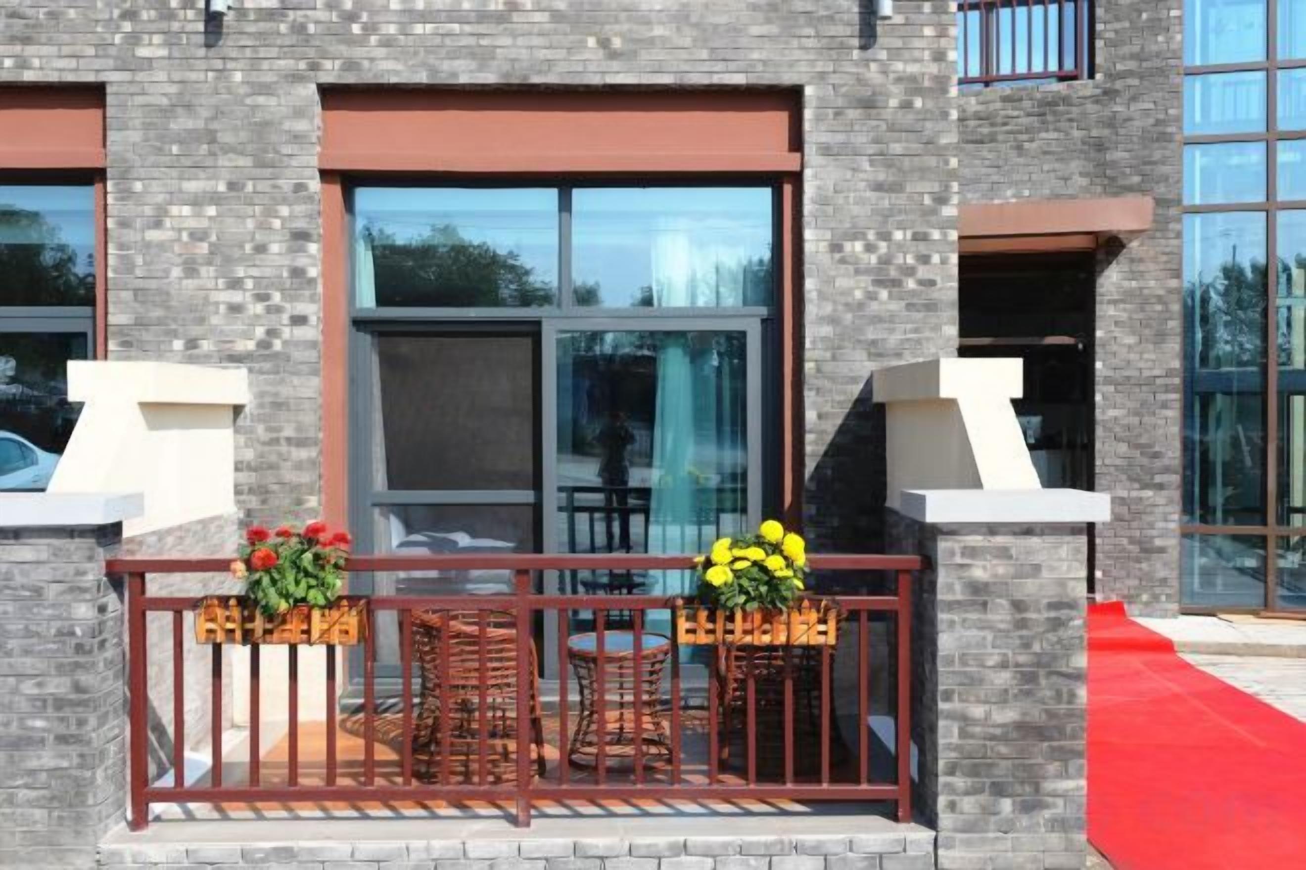 A building with a balcony, large windows, and outdoor seating.