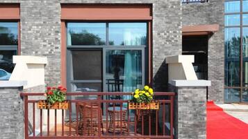 A building with a balcony, large windows, and outdoor seating.