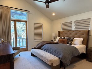 A bedroom with a large bed, a desk, and a ceiling fan.