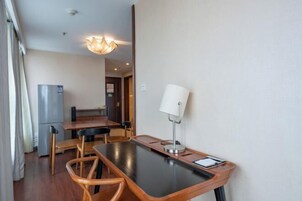 Una habitación compacta con una mesa de comedor, sillas, lámpara, refrigerador y una puerta que da a otra habitación.