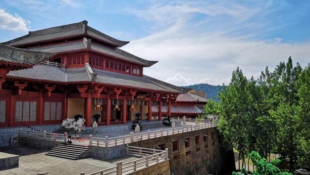 A traditional building with a multi-tiered roof, a stone pathway, and a wooden railing. - Bedom Apartment (Hengdian Nanjiang No. 1 Branch) (Dongyang)