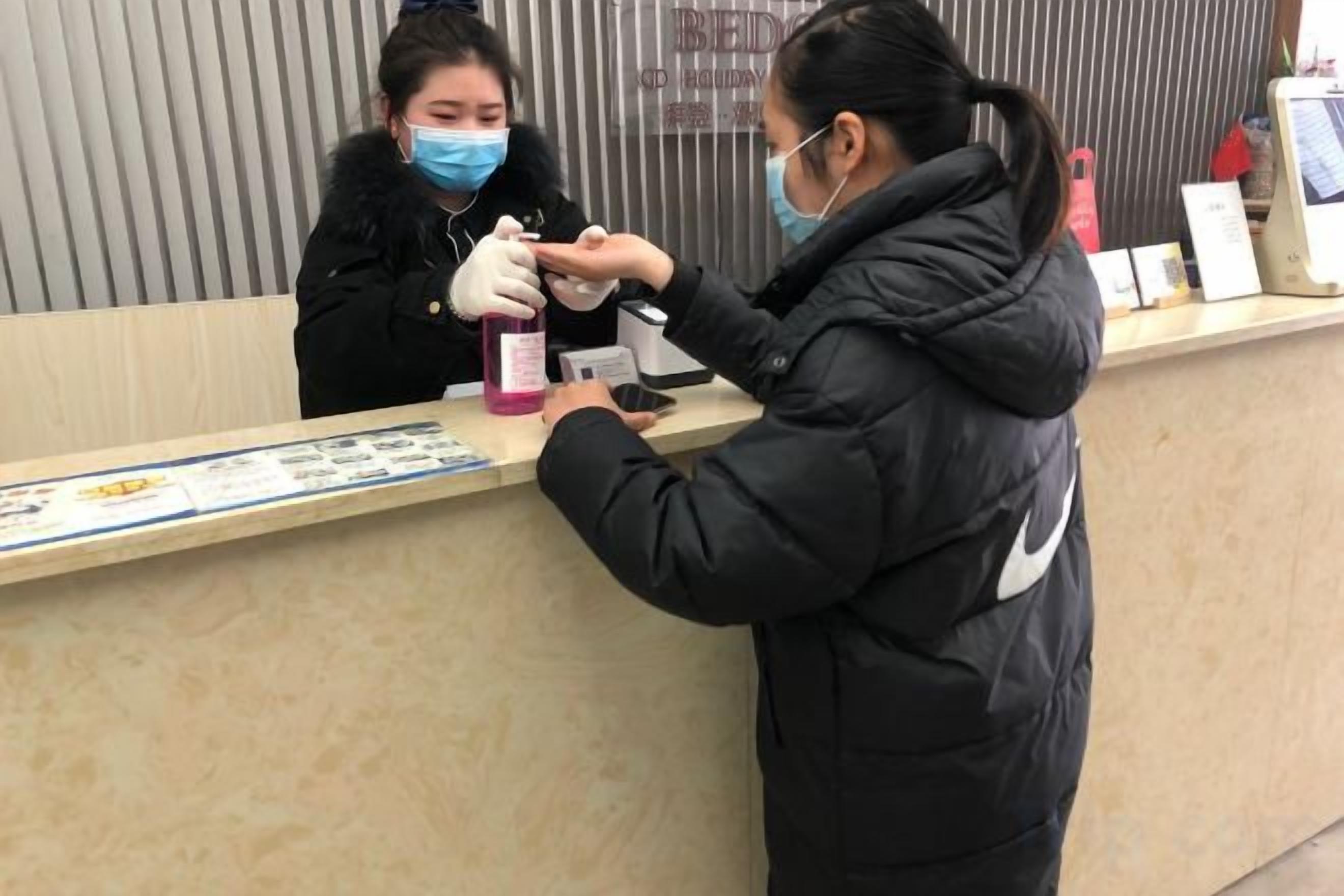A reception desk with a counter, a person wearing a black jacket, and another person in a black coat.