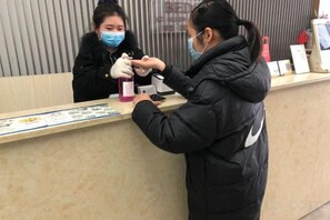 A reception desk with a counter, a person wearing a black jacket, and another person in a black coat.