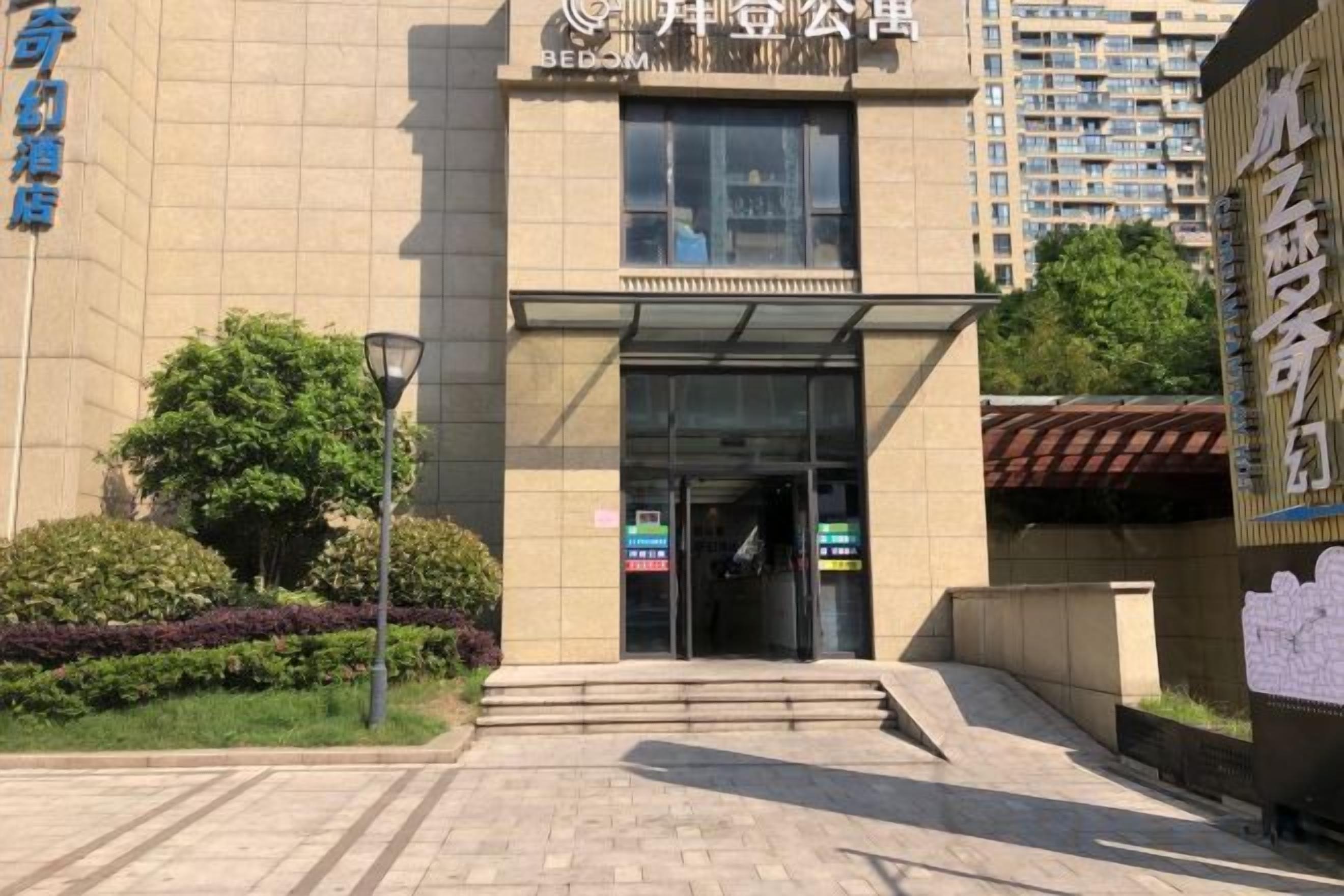 Entrada de um edifício com porta de vidro, degraus de acesso e uma placa acima da porta.