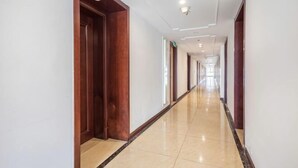 A long, narrow hallway with wooden doors and a tiled floor. - Bedom Apartment (Hengdian Nanjiang No. 1 Branch) (Dongyang)