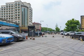 Un estacionamiento con varios automóviles, un edificio con señalización y un cielo despejado.