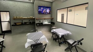 Ein Konferenzraum mit Tischen, Stühlen, einem Fernseher und einer Küchenzeile.