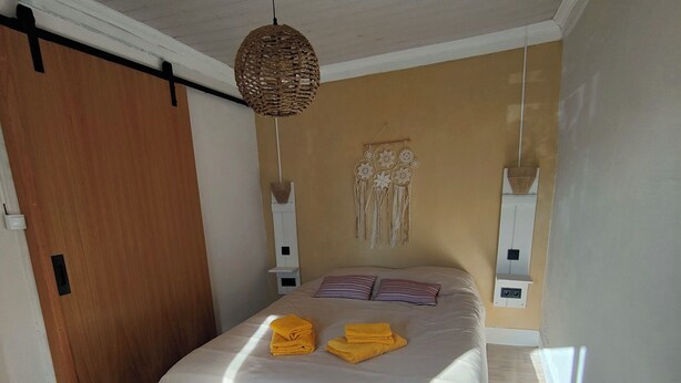 Une chambre à coucher avec un lit, un plancher en bois et un luminaire au plafond.
