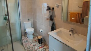 Une salle de bain avec une douche à parois de verre, des toilettes, un lavabo avec un miroir et des carreaux de sol à motifs.