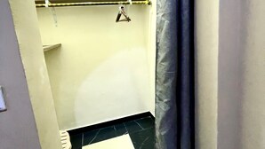 Un couloir étroit avec un sol à carreaux noirs et blancs, un porte-serviettes et un rideau de douche.