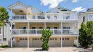 A two-story residential building with a balcony on each floor, a garage, and a small tree in the front yard. - Beautiful, 3 bed, 2 bath, Cozy Condo just minutes from Boardwalk & Beach Access! (Wildwood)
