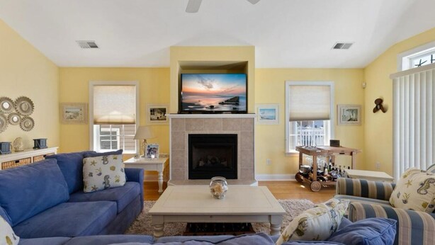 A living room with a fireplace, a television mounted above it, and a ceiling fan. - Beautiful, 3 bed, 2 bath, Cozy Condo just minutes from Boardwalk & Beach Access! (Wildwood)