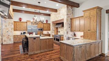 A spacious kitchen with wooden cabinets, a large island, and a stone accent wall.