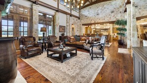 A spacious living room with leather sofas, a coffee table, and a large rug. There are wooden beams on the ceiling and stone walls. - Private Ranch - Pool, Ping Pong, Yoga, Weddings, Games (Bergheim)