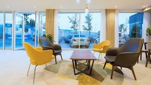 A modern hotel lobby with a central seating area, large windows, and a view of the parking lot. - HanTing Premium Hotel (Dalian North Station) (Dalian)