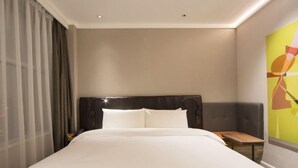 A hotel room with a large bed, a nightstand, a small table, and a window with curtains. - HanTing Premium Hotel (Dalian North Station) (Dalian)