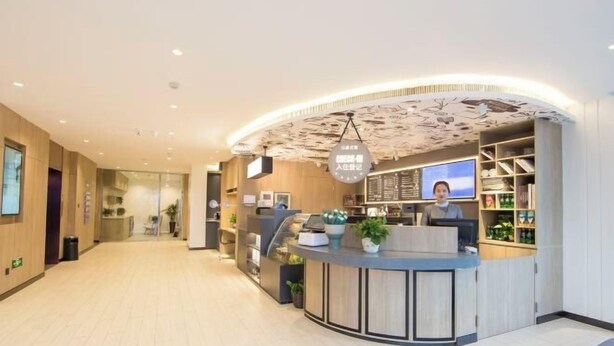 A modern reception area with a curved counter, a digital screen, and a ceiling with a unique pattern. - HanTing Premium Hotel (Dalian North Station) (Dalian)