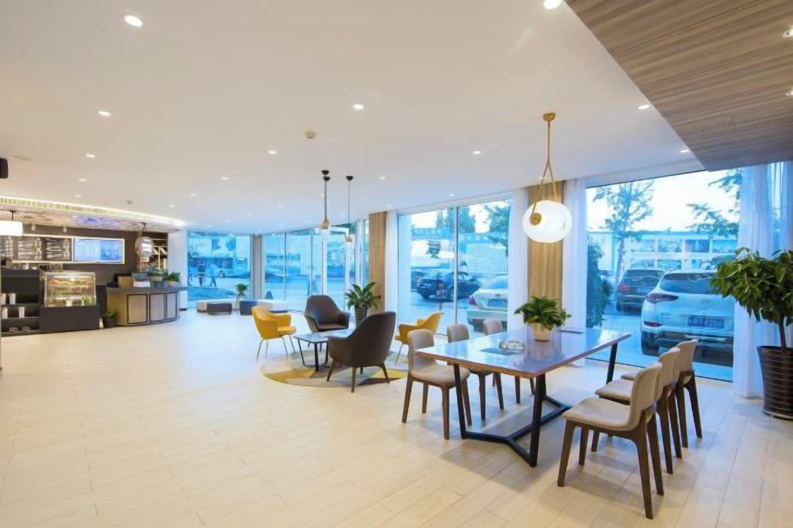 Un hall d’hôtel moderne doté d’un espace repas, de grandes fenêtres et d’un comptoir d’accueil.