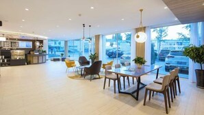 A spacious hotel lobby with a reception desk, seating area, and large windows offering a view of parked cars outside. - HanTing Premium Hotel (Dalian North Station) (Dalian)
