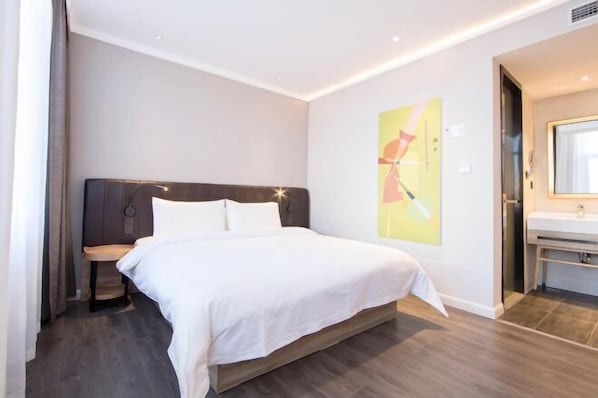A modern hotel room with a large bed, a bedside table, a wall-mounted artwork, and a bathroom with a sink and mirror. - HanTing Premium Hotel (Dalian North Station) (Dalian)