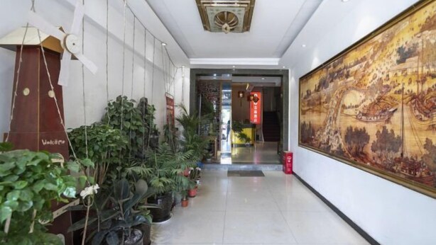Un couloir agrémenté de plantes en pot, orné d’une grande peinture murale et doté d’un ventilateur de plafond.