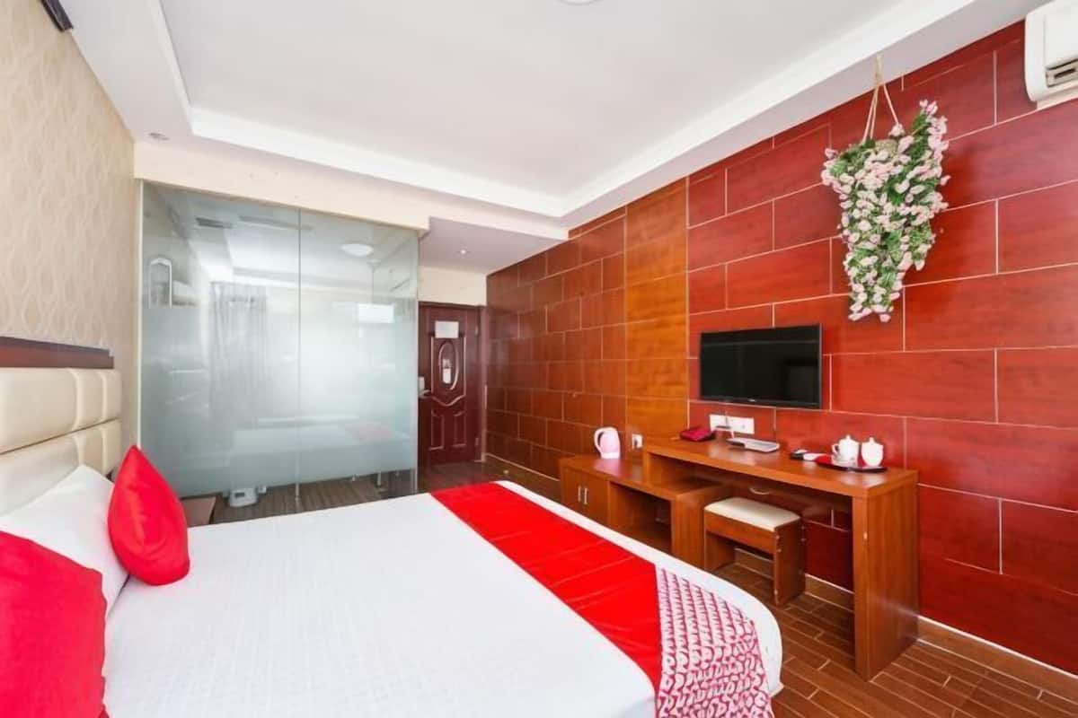 A hotel room with a bed, a desk, a TV, and a red brick wall.
