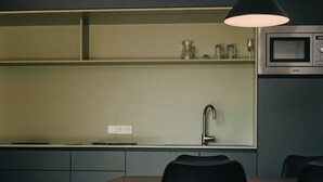 A compact kitchen with a microwave, a sink, and a dining area with a table and chairs.