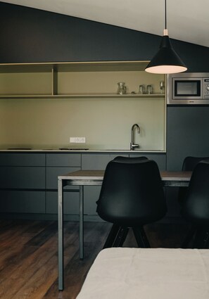 Eine kompakte Küche mit Mikrowelle, Spüle und Essbereich mit Tisch und Stühlen.