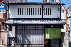 Un bâtiment japonais traditionnel, doté d’un toit recouvert de tuiles, de grandes portes coulissantes et d’un auvent vert.