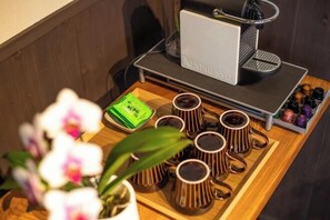 A coffee station with a Nespresso machine, several cups, and a tray with coffee pods and a green packet. - Hiyori Gojo (Kyoto)