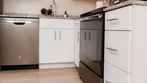 Een moderne keuken met witte kasten, roestvrijstalen apparatuur en een granieten aanrecht.