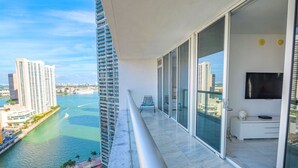 A balcony with a view of a river and buildings, a chair, and a TV. - Icon Brickell - Panoramic Views - Spa Access (Miami)