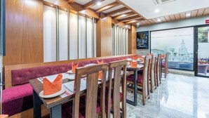 A restaurant with wooden paneling, cushioned seating, and a view of a temple through the window. - Hotel Kutumba (Lalitpur)