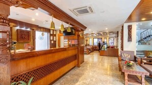 A reception area with a wooden reception desk, pendant lighting, and a marble floor. - Hotel Kutumba (Lalitpur)