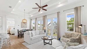 A spacious living room with a white sofa, a patterned armchair, a round coffee table, and a ceiling fan. - ☀️ 2 Resort Pools | 6 Seater Golf Cart | Bikes | Near The Big Chill 🛍️ (Inlet Beach)