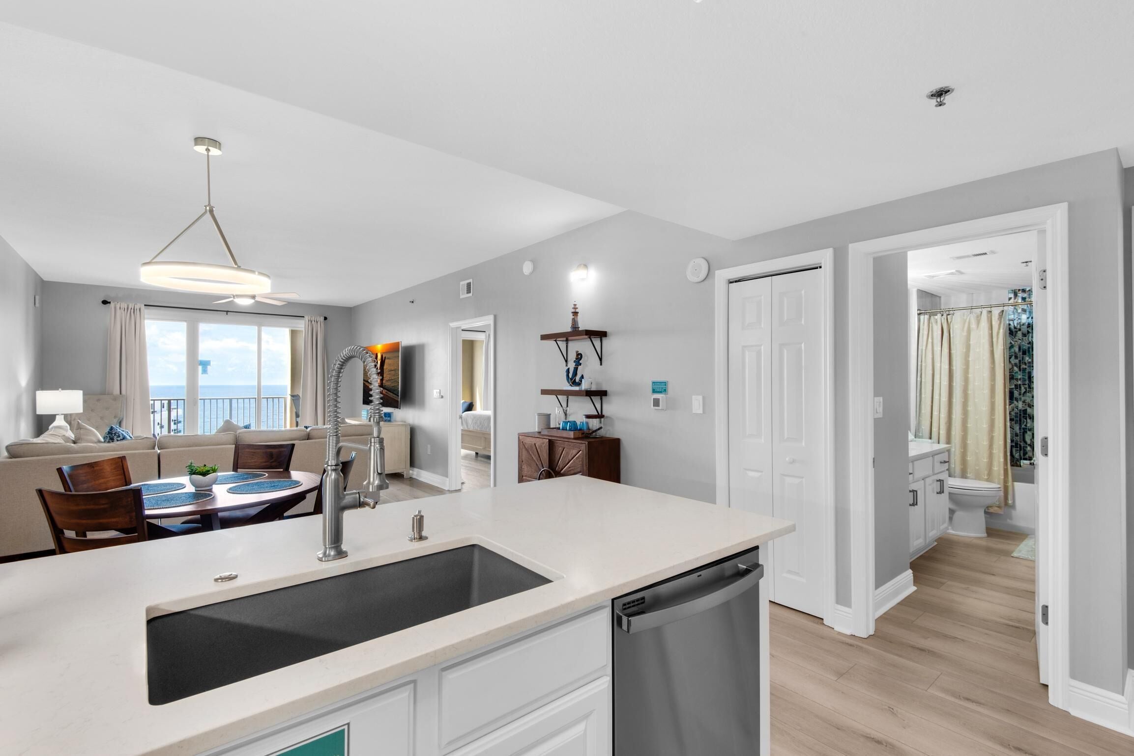 A modern kitchen with a large island, a dining area with a table and chairs, and a view to the outside.