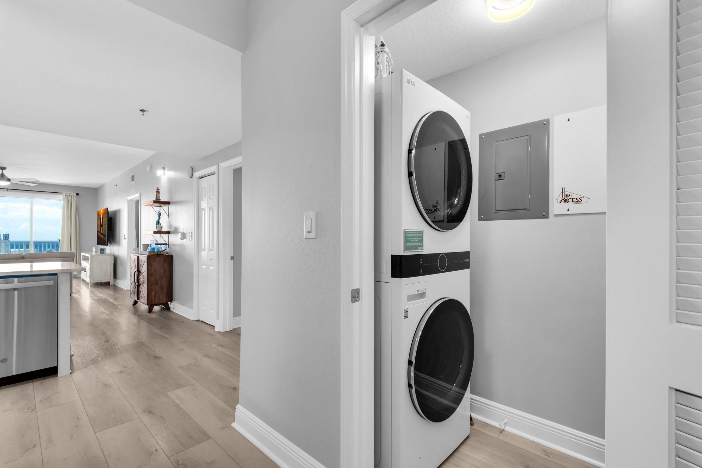 Una sala de bugaderia amb dues piles de rentadores i assecadores, vista de la cuina, i una porta que dona a una altra habitació.