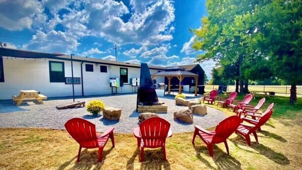 A building with a patio area featuring outdoor seating and a barbecue grill. - The Bike Inn #16, White River Cabin (Bentonville)