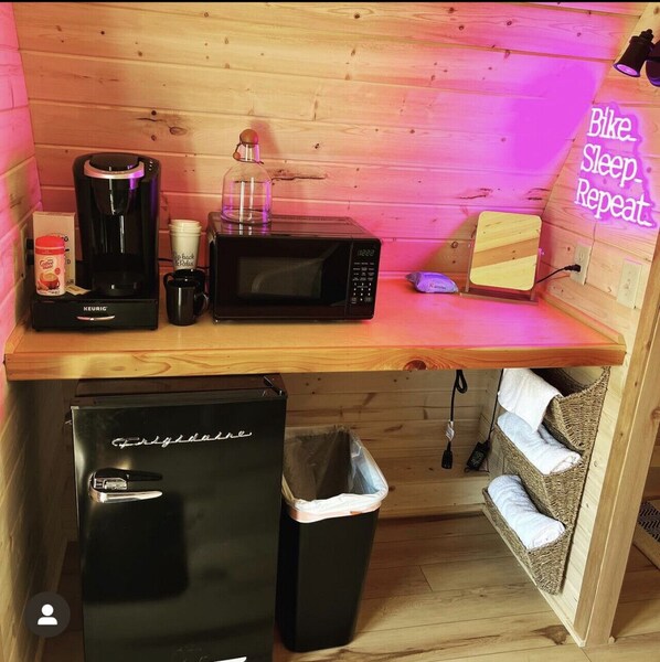 Eine kompakte Küchenzeile mit Kaffeemaschine, Mikrowelle, Toaster und Mülleimer.