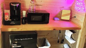 A kitchenette with a coffee maker, microwave, toaster, and trash bin. - The Bike Inn #16, White River Cabin (Bentonville)